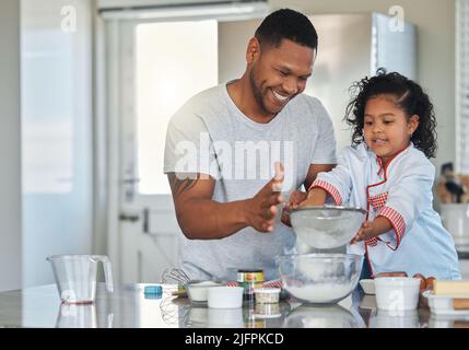 Backen ist eine Gelegenheit, Zeit mit einem geliebten Menschen zu teilen. Aufnahme eines Vaters, der mit seiner Tochter zu Hause backt. Stockfoto