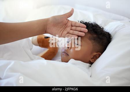 Das Wichtigste auf der Welt ist die Familie. Aufnahme einer unkenntlichen Frau, die ihre Söhne in Tempretur nimmt. Stockfoto