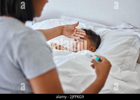 Die Temperatur steigt. Aufnahme einer unkenntlichen Frau, die ihre Söhne in Tempretur nimmt. Stockfoto