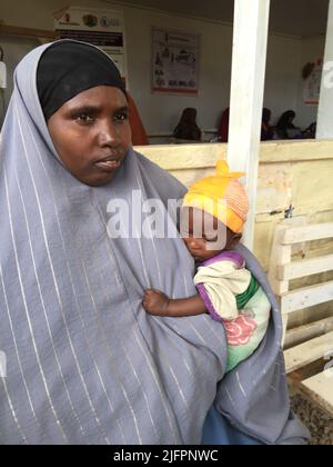 Baidoa, Somalia. 29.. Juni 2022. Nala Hassan hält ihren kleinen Sohn Rachid in den Armen. Die somalische Mutter ist mit dem stark unterernährten Baby in einer Klinik in Baidoa im Südwesten Somalias. Eine schwere Dürre hat eine Hungerkrise ausgelöst. Insbesondere die Zahl der lebensbedrohlichen unterernährten Säuglinge ist in den letzten Wochen stark gestiegen. (To dpa 'Wettlauf gegen die Zeit, um das Leben hungernder Kinder zu retten') Quelle: Eva-Maria Krafczyk/dpa/Alamy Live News Stockfoto