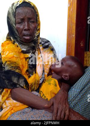 Baidoa, Somalia. 29.. Juni 2022. Die 60-jährige Waris Abdi sitzt mit ihrem zweijährigen Enkel Mohamed im Sahal-Macalin-Stabilisierungszentrum in Baidoa im Südwesten Somalias. Die Spezialklinik kümmert sich um stark unterernährte Kinder. Somalia befindet sich seit Monaten in einer schweren Dürre, wobei vier aufeinanderfolgende Regenzeiten nicht eingetreten sind. Vor allem kleine Kinder sind vom Hungertod bedroht. (To dpa 'Wettlauf gegen die Zeit um das Leben hungernder Kinder') Quelle: Eva-Maria Krafczyk/dpa/Alamy Live News Stockfoto