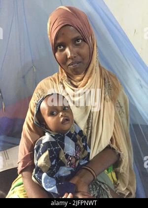 Baidoa, Somalia. 29.. Juni 2022. Habiba Ali, eine junge Mutter aus Somalia, mit ihrer jungen Tochter im Sahal-Macalin-Stabilisierungszentrum in Baidoa im Südwesten Somalias. Die Spezialklinik kümmert sich um stark unterernährte Kinder. Eine schwere Dürre hat eine Hungerkrise ausgelöst. Insbesondere die Zahl der lebensbedrohlichen unterernährten Säuglinge ist in den letzten Wochen stark gestiegen. (To dpa 'Wettlauf gegen die Zeit, um das Leben hungernder Kinder zu retten') Quelle: Eva-Maria Krafczyk/dpa/Alamy Live News Stockfoto