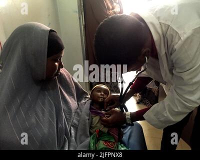 Baidoa, Somalia. 29.. Juni 2022. Ein Arzt in einer Klinik in Baidoa im Südwesten Somalias untersucht das Baby Rachid. Der kleine Junge ist stark unterernährt und benötigt dringend spezielle Nahrung. Nach monatelanger Dürre und vier ungenügenden Regenzeiten in Folge sind vor allem junge Kinder in dem Land am Horn von Afrika vom Hungertod bedroht. (To dpa 'Wettlauf gegen die Zeit um das Leben hungernder Kinder') Quelle: Eva-Maria Krafczyk/dpa/Alamy Live News Stockfoto