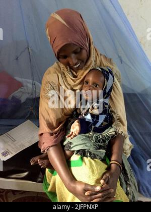 Baidoa, Somalia. 29.. Juni 2022. Habiba Ali, eine junge Mutter aus Somalia, mit ihrer jungen Tochter im Sahal-Macalin-Stabilisierungszentrum in Baidoa im Südwesten Somalias. Die Spezialklinik kümmert sich um stark unterernährte Kinder. Eine schwere Dürre hat eine Hungerkrise ausgelöst. Insbesondere die Zahl der lebensbedrohlichen unterernährten Säuglinge ist in den letzten Wochen stark gestiegen. (To dpa 'Wettlauf gegen die Zeit, um das Leben hungernder Kinder zu retten') Quelle: Eva-Maria Krafczyk/dpa/Alamy Live News Stockfoto