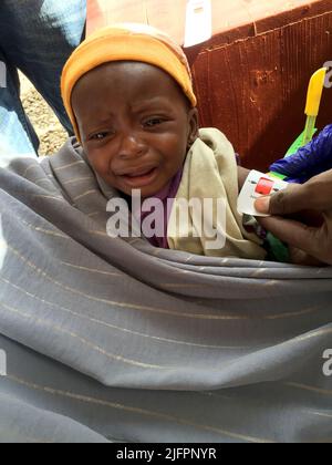 Baidoa, Somalia. 29.. Juni 2022. Ein Mitarbeiter einer Klinik in Baidoa im Südwesten Somalias misst den Umfang des Armes von Little Rachid. Das Baby ist stark unterernährt und braucht dringend eine spezielle Ernährung. Nach monatelanger Dürre und vier ungenügenden Regenzeiten in Folge sind vor allem junge Kinder in dem Land am Horn von Afrika vom Hungertod bedroht. (To dpa 'Wettlauf gegen die Zeit um das Leben hungernder Kinder') Quelle: Eva-Maria Krafczyk/dpa/Alamy Live News Stockfoto