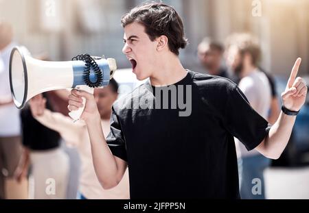 Wir werden nicht zum Schweigen gebracht werden. Aufnahme eines jungen Mannes, der während eines Protestes durch ein Megaphon schreit. Stockfoto