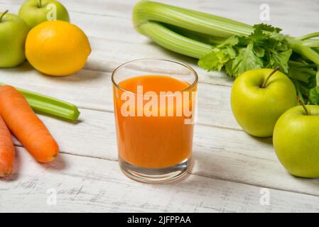 Karotten-Apfel und Sellerie-Saft auf einem weißen alten Tisch mit Zutaten. Ausgewählter Fokus. Stockfoto