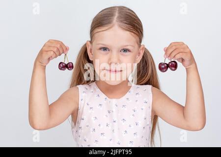 Kaukasisches kleines Mädchen von 6 Jahren mit süßer Kirsche auf weißem Hintergrund Stockfoto