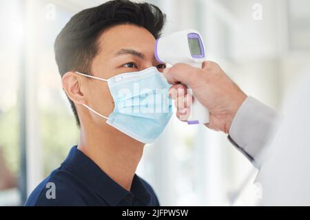 Überwachen Sie Ihre Temperatur, um sicher zu sein. Aufnahme eines nicht erkennbaren Arztes, der die Temperatur eines Patienten in einem Krankenhaus einnahm. Stockfoto