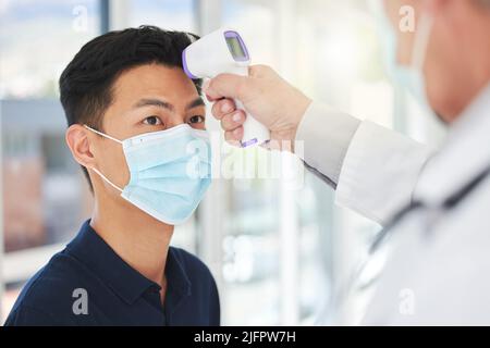 Überprüfen Sie Ihre Temperatur. Aufnahme eines nicht erkennbaren Arztes, der die Temperatur eines Patienten in einem Krankenhaus einnahm. Stockfoto