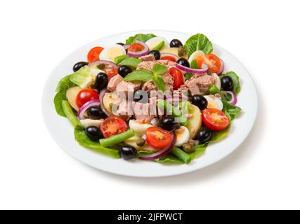 Nicoise Salat mit Thunfisch, Tomaten, Salat, Oliven auf einem weißen Teller isoliert auf weißem Hintergrund. Nahaufnahme. Stockfoto