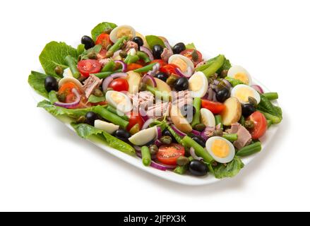 Traditioneller Nicoise-Salat in einer weißen rechteckigen Salatschüssel isoliert auf weißem Hintergrund. Stockfoto