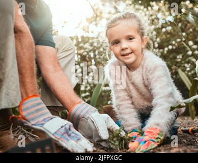 Die Liebe zum Gartenbau. Aufnahme eines entzückenden kleinen Mädchens, das mit ihrem Großvater im Garten arbeitet. Stockfoto