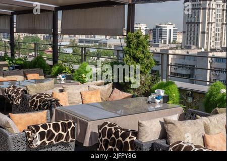 Dachbar mit Blick auf den herrlichen blauen Himmel der Stadt. Café auf dem Dach des Gebäudes. Tisch auf dem Dach Restaurant mit Blick auf die Megapolis. b Stockfoto