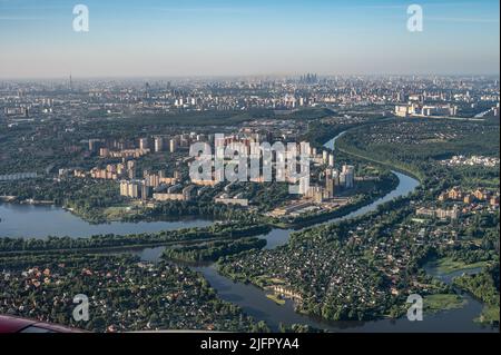 Luftaufnahmen einer großen Stadt aus einem Flugzeugfenster. Blick auf die moderne Stadt vom Flugzeugfenster aus Stockfoto