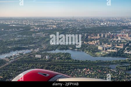 Luftaufnahmen einer großen Stadt aus einem Flugzeugfenster. Blick auf die moderne Stadt vom Flugzeugfenster aus Stockfoto