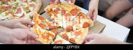 Die Hände der großen Firma nehmen ein Stück rund geformte Pizza Stockfoto