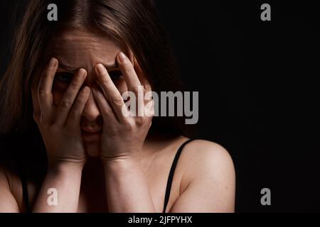 Es passiert wieder. Aufnahme einer Frau, die vor einem dunklen Hintergrund verängstigt aussagt. Stockfoto