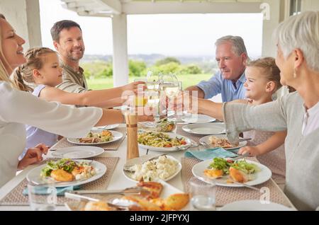 Denken Sie daran, Augenkontakt zu haben. Aufnahme einer Familie beim Toasten während eines sonntagsmittags. Stockfoto