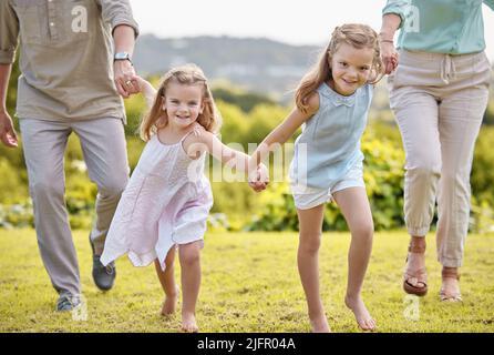 Die Dinge, die wichtig sind, sind Glaube, Familie und Freunde. Aufnahme eines Paares mit ihren beiden Töchtern, die zusammen in einem Park posieren. Stockfoto