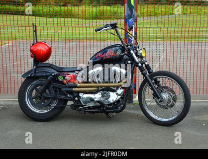 Harley Davidson Motorrad vor Metall Grillzaun geparkt. Stockfoto