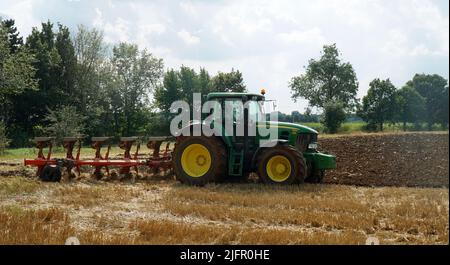 Grüner John Deere-Traktor, der in Stoppeln pflügt. Stockfoto