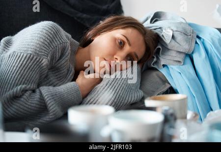 Keine Motivation, etwas zu tun. Aufnahme einer depressiven jungen Frau, die auf ihrer unordentlichen Couch liegt. Stockfoto