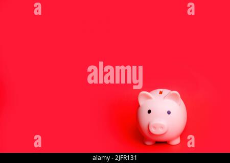 Rosa Sparschwein isoliert vor rotem Hintergrund Stockfoto