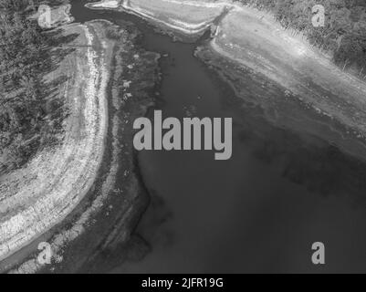 Ein Vogelschwarm fliegt über einen Teil des Wassereindämmungsgebiets des Eungella Dam, Queensland, Australien. Texturen und Muster im Wasser sichtbar durch Stockfoto