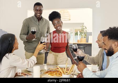 Wir haben eine spezielle Ankündigung mit unseren Freunden geteilt. Aufnahme einer Gruppe von Leuten, die am Esstisch in einem Haus toasten. Stockfoto