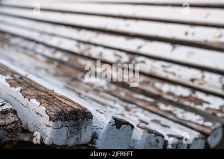 Nahaufnahme einer alten verwitterten Holzbank. Nahaufnahme der Kante, Details von abblätternder weißer Farbe und Holzmaterial. Seitenansicht. Stockfoto