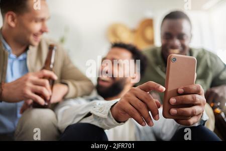 Soll ich es Euch schicken? Aufnahme von drei männlichen Freunden, die zusammen etwas auf einem Handy angeschaut haben. Stockfoto