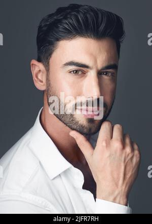 Das perfekte professionelle Profilbild. Studioaufnahme eines hübschen jungen Mannes, der vor einem grauen Studiohintergrund posiert. Stockfoto