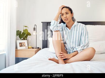 Lassen Sie sich nicht von Ihren Gedanken kontrollieren. Aufnahme einer jungen Frau, die besorgt aussieht, während sie auf ihrem Bett bei Homer sitzt. Stockfoto
