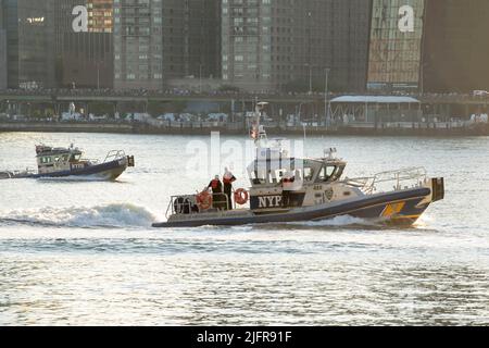 NEW YORK, NY – JULI 04: Ein Boot der New Yorker Polizeibehörde (NYPD) patrouilliert am East River während der jährlichen Macy's Feuerwerksaufstellung vom 4.. Juli 46. mit Blick auf die Skyline von Manhattan am Gantry State Plaza in Long Island City am 4.. Juli 2021 im Stadtteil Queens von New York City. Die jährliche Macy’s Feuerwerksfeier vom 4.. Juli 46. umfasste mehr als 48.000 Muscheln und Effekte von fünf Lastkähne und dauerte etwa 25 Minuten. Stockfoto