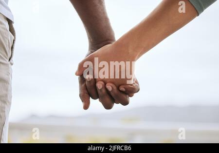 Nahaufnahme des Birazialpaares, das sich mit den Fingern verzapft und die Hände hält, während es sich im Freien verklebt. Fürsorgliche Mischrasse Frau mit afroamerikanischem Mann vereint Stockfoto