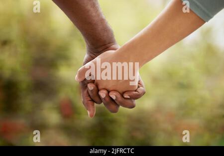 Nahaufnahme eines Birazialpaares, das seine Finger verzapft und die Hände hält, während es sich im Garten zu Hause festhält. Mischrasse Frau mit Afrikaner vereint Stockfoto