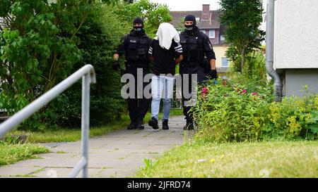 05. Juli 2022, Niedersachsen, Osnabrück: Ein Festgenommenen wird von der Polizei mitgenommen. Hunderte von Polizisten haben am Dienstagmorgen gegen Schmuggelbanden vorgebracht. Zahlreiche Durchsuchungen und Verhaftungen gab es in der Nähe von Osnabrück in Bremen und Stuttgart sowie in Großbritannien, Frankreich, Belgien und den Niederlanden. (To dpa: 'Hunderte von Polizisten im Einsatz gegen Schmuggelbanden') Foto: Festim Beqiri/Tv7news/dpa Stockfoto