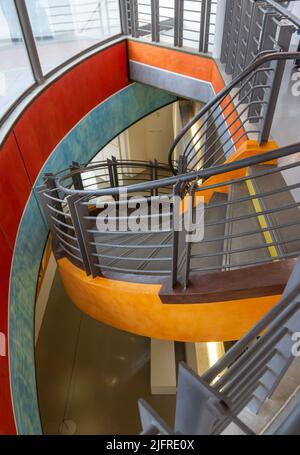 Bild von oben von verdrehten Treppen mit moderner Architektur, zahlreichen und lebendigen Farben und einem Eisengeländer. Stockfoto