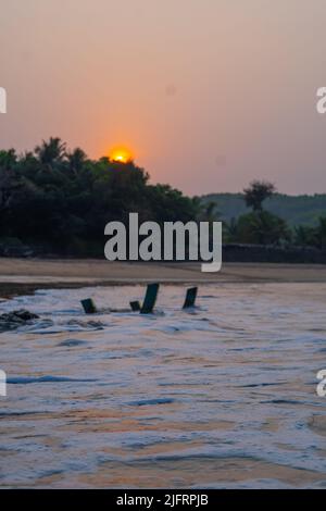 Weißer Schaum, der sich bei Sonnenaufgang am Strand von Om ausbreitet Stockfoto