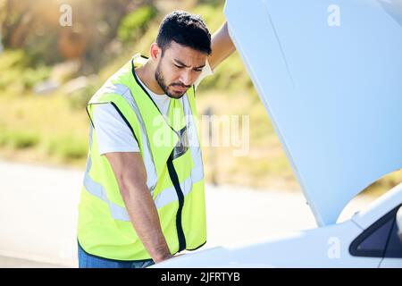Versicherungen sind von entscheidender Bedeutung. Aufnahme eines jungen Mannes, der nach einem Fahrzeugausfall unter der Motorhaube seines Autos nachprüfte. Stockfoto