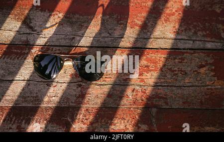 Sonnenbrillen für Geschäfte auf einem roten Holzhintergrund mit Lichtstrahlen. Stockfoto