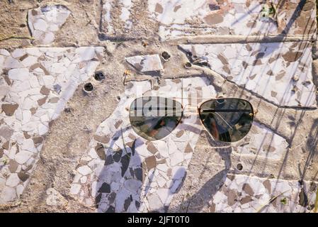 Sonnenbrillen für Geschäfte auf steinernem Hintergrund mit Lichtstrahlen Stockfoto