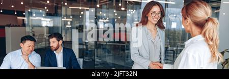 Zwei Arbeiterinnen schütteln sich in modernen Büros während der Besprechung die Hände Stockfoto