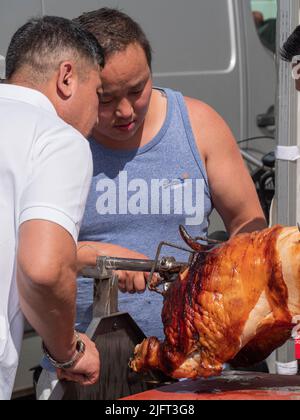 Antwerpen, Belgien, 02. Juli 2022, schnitten zwei Männer ein gegrilltes Spanferkel auf einem Spieß Stockfoto