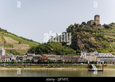 Die Stadt Kaub (Caub) am Rhein mit Weinterrassen/Weinbergen und Schloss Gutenfels im Hintergrund. Stockfoto