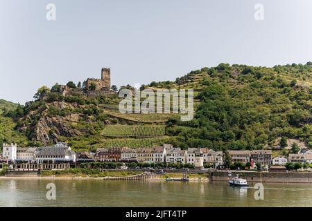 Die Stadt Kaub (Caub) am Rhein mit Weinterrassen/Weinbergen und Schloss Gutenfels im Hintergrund. Stockfoto