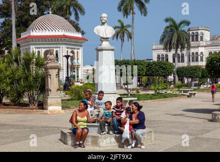 Kuba, Manzanillo. Auf dem zentralen Platz, Parque Carlos Manuel de Cespedes, stehen Mütter mit Kindern vor der Statue von Carlos Manuel de Céspe Stockfoto