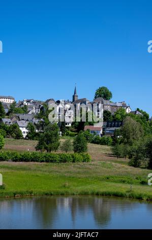 Stadt La-Tour-d'Auvergne im Frühjahr am Rande seines Sees in den Bergen der Auvergne im Département Puy-de-Dome in Frankreich im Massif-Cen Stockfoto