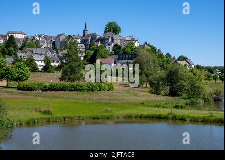 Stadt La-Tour-d'Auvergne im Frühjahr am Rande seines Sees in den Bergen der Auvergne im Département Puy-de-Dome in Frankreich im Massif-Cen Stockfoto